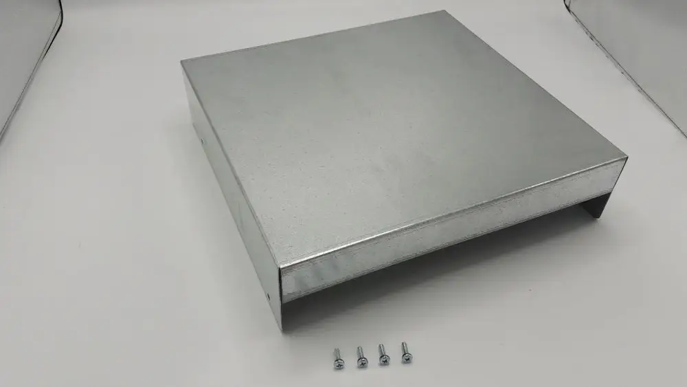 Eckiger, metallischer Deckel mit mehreren Kanten und verschraubbaren Löchern, geeignet für Regelungsgehäuse von Remeha. Sechs kleine Schrauben liegen daneben.